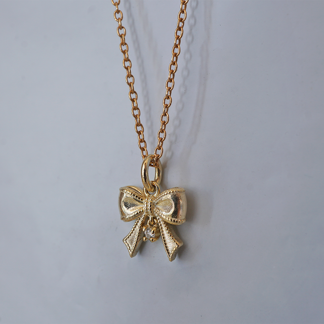 The Bow ribbon charm on a gold chain