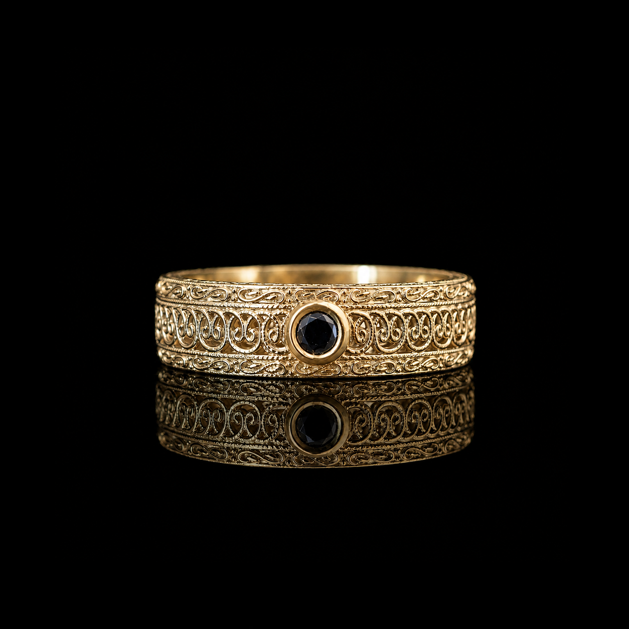 An ornate gold filigree ring with a central round black diamond, displayed on a reflective black surface against a solid black background.