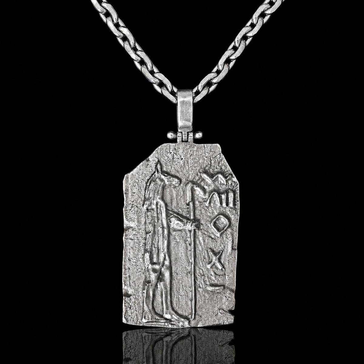A silver pendant necklace featuring an ancient Egyptian-style hieroglyphic plaque with a pharaoh figure, suspended from a thick chain against a solid black background.