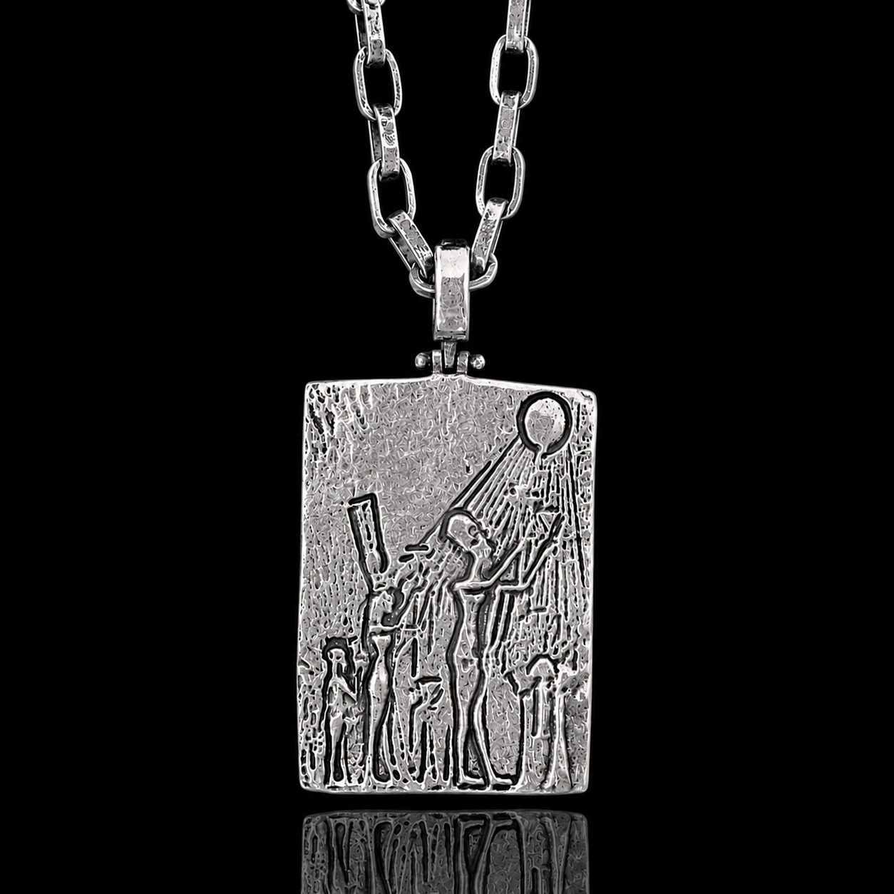 A rectangular silver pendant necklace featuring an embossed relief design of a figure, set against a black background with a subtle reflection below.