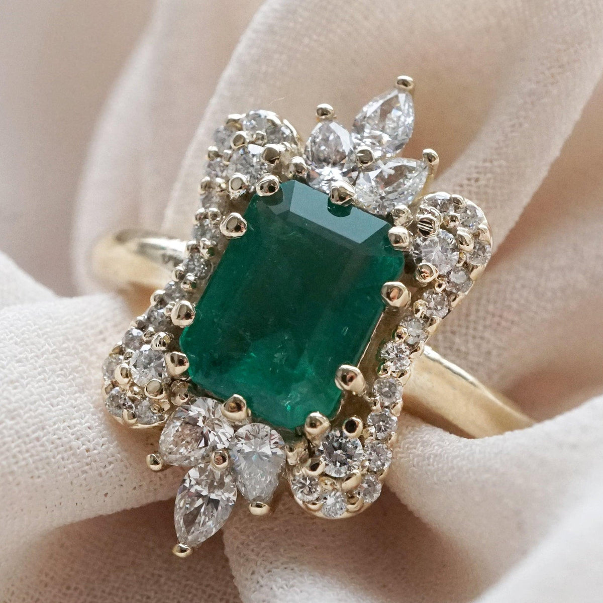 Pear-shaped diamonds fanning above and below the emerald center stone of the Eleanor ring