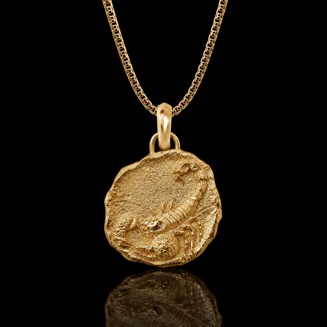 A gold pendant necklace featuring an ancient coin-style charm with a raised scorpion design, suspended from a gold chain against a solid black background with a soft reflection below.
