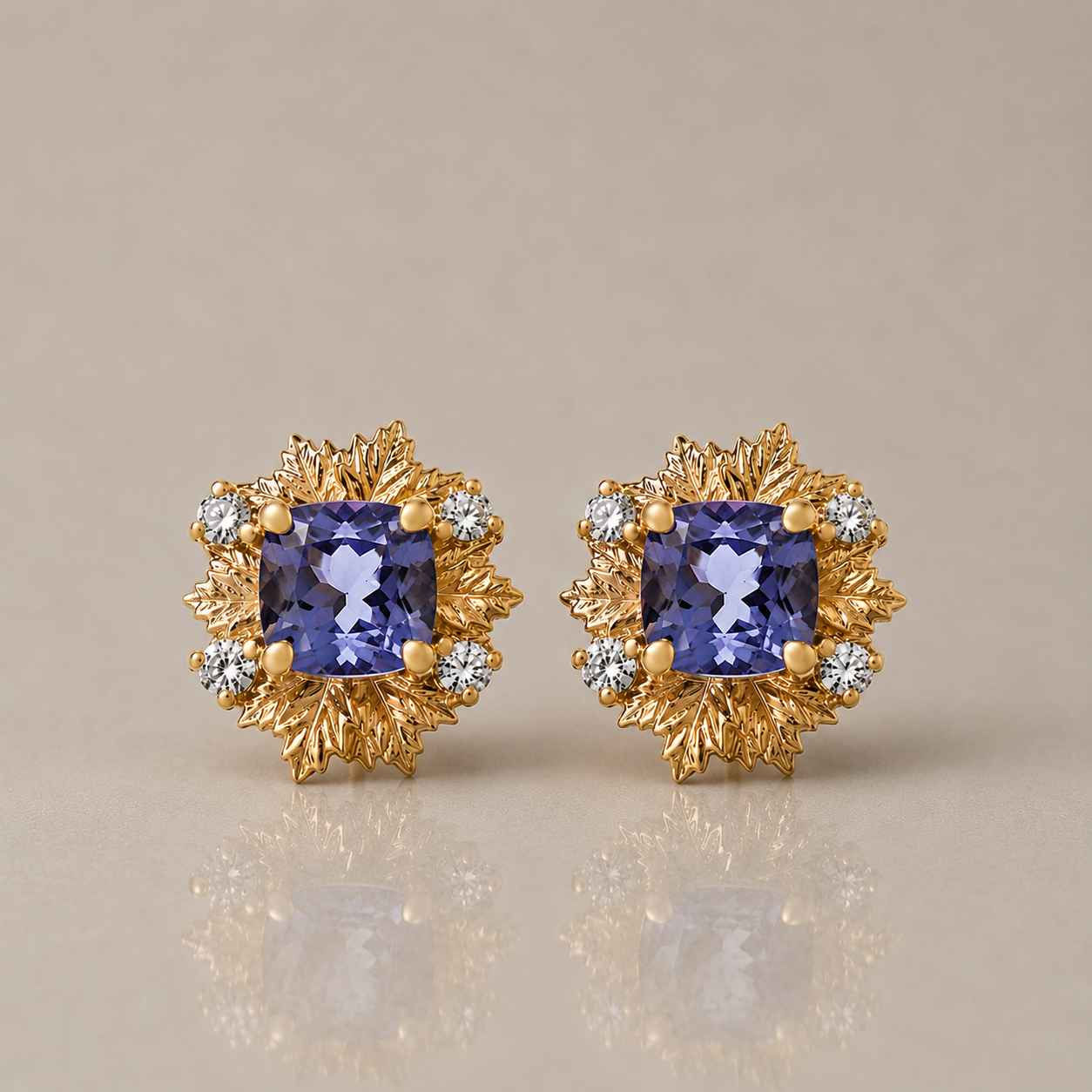 A pair of gold-toned stud earrings featuring square blue tanzanite center stones surrounded by leaf-shaped gold settings and small diamonds, shown on a warm beige background with a soft reflection below.