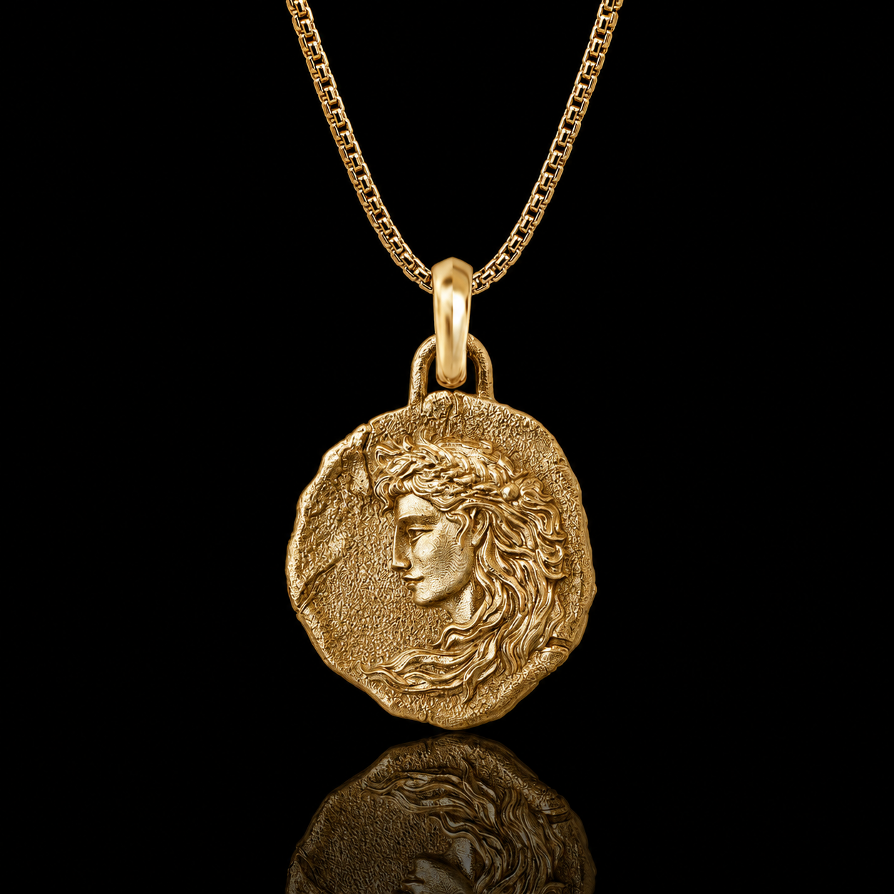 A gold pendant necklace featuring an ancient coin-style medallion with a profile portrait, suspended from a gold chain against a solid black background with a soft reflection below.